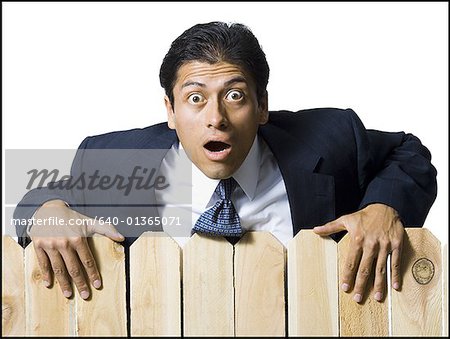 Businessman looking over wooden fence