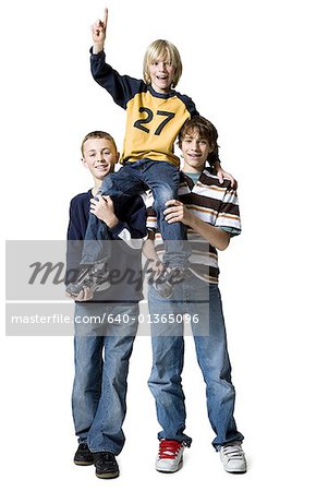 Portrait of two boys carrying a boy on their shoulders