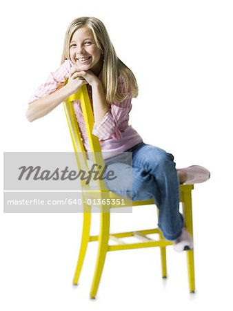 Portrait d'une jeune fille assise sur une chaise et souriant