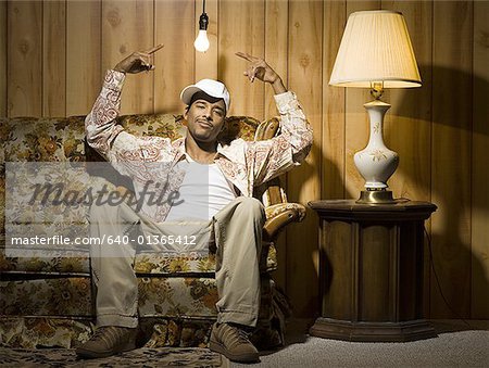 Homme assis sur un canapé sous ampoule pointant vers le haut