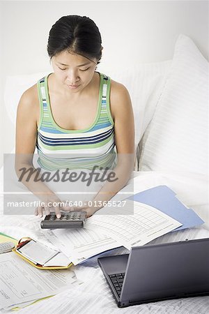 High angle view of a mid adult woman using a calculator