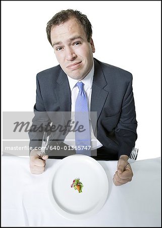 Vue grand angle d'un jeune homme assis à la table à manger et en maintenant une fourchette