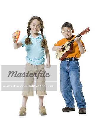 Portrait d'un garçon jouant de la guitare avec une jeune fille debout à côté de lui