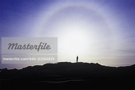 A silhouette of a person standing on top of a mountain