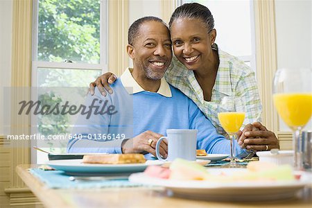 Portrait d'une femme et un homme souriant à la table du petit déjeuner