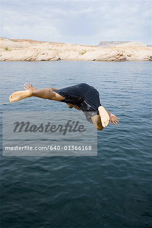 Young man jumping into a lake