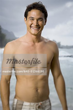 Portrait d'un jeune homme debout sur la plage et souriant