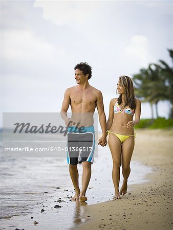 Young couple holding hands and walking on the beach