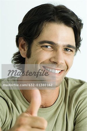 Homme souriant à la caméra, donnant les pouces vers le haut le signal, tête et épaules, portrait