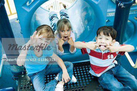 Children on playground equipment, making faces at camera