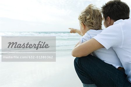Man looking at ocean with son, rear view