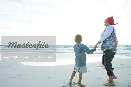 Senior woman standing on beach with grandson