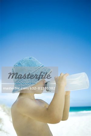 Boy drinking from water bottle on beach