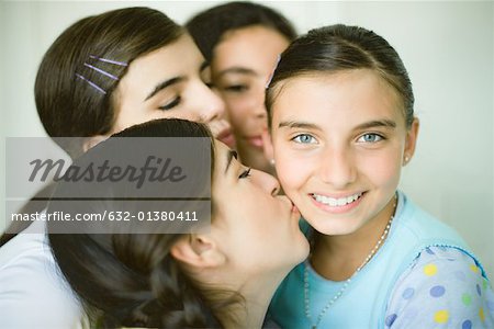 Vier junge Freundinnen, drei eines Mädchens Wange küssen