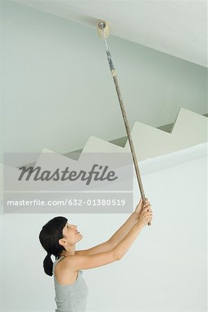 Plafond peinture femme avec un rouleau de peinture