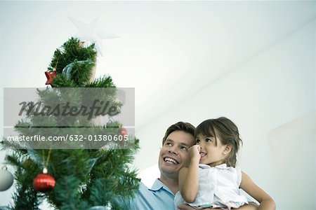 Père et fille plaçant étoile au sommet du sapin de Noël