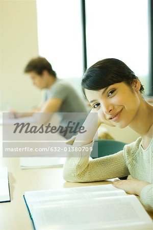 Weibliche College-Student sitzen am Tisch mit Buch, lächelnd in die Kamera