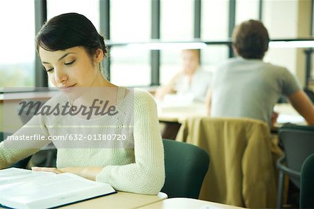 Female college student sitting at table in library, studying