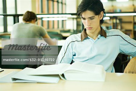 Male college student sitting library, studying