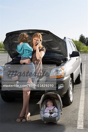 Mère avec enfants ayant la voiture tombe en panne et en utilisant le téléphone cellulaire pour les appels à l'aide