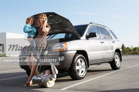 Mother with Children Having Car Trouble and Using Cell Phone to Call for Help