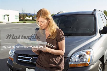 Frau stehend vor Auto, Blick auf die Straßenkarte