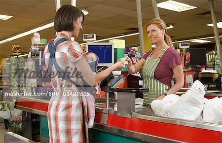 Mutter mit Baby an der Kasse im Supermarkt