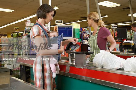 Mutter mit Baby an der Kasse im Supermarkt