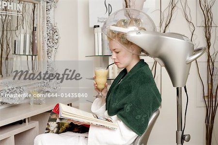 Jeune femme assise sous le sèche-cheveux