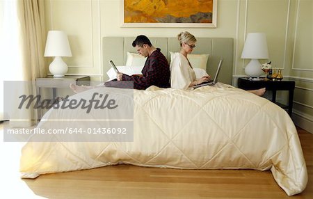 Mature couple working in bed