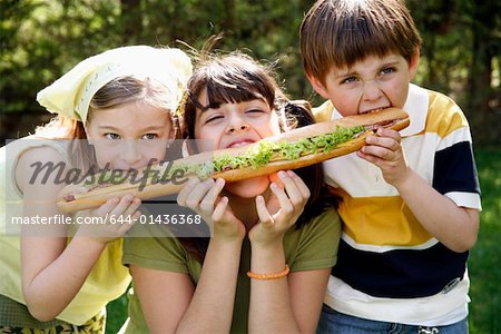 Three children sharing a large sandwich