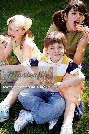 Three children eating pizza