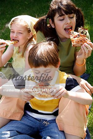 Three children eating pizza