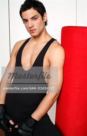 Young man leaning on punching bag