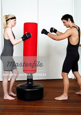 Jeune homme et une femme pratiquant avec un sac de boxe