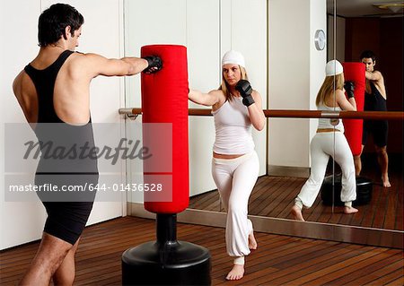 Young man and woman hitting the punching bag
