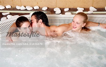 Ein Mann mit zwei Frauen in einem Spa Whirlpool