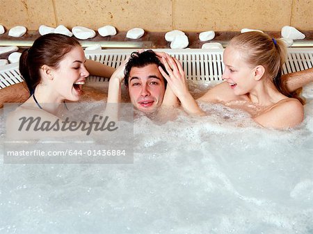 Ein Mann mit zwei Frauen in einem Spa Whirlpool