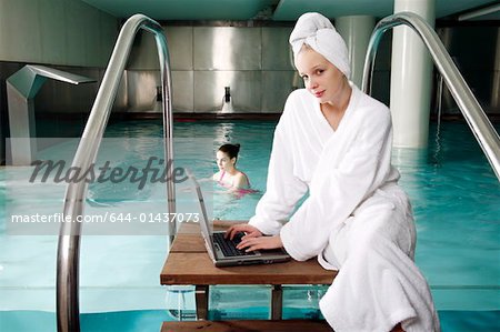 Woman on computer next  to a swimming pool