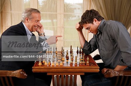 Mature man and younger man playing chess