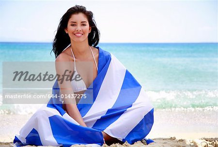 Jeune femme sur la plage, enveloppée dans le drapeau grec