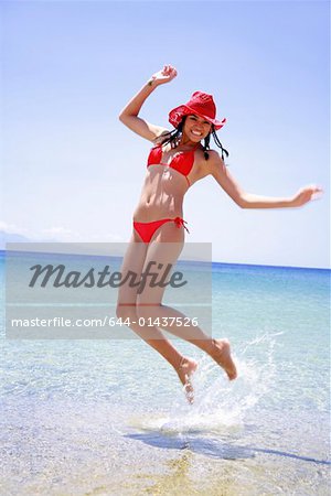Jeune femme en bikini et chapeau saute en l'air