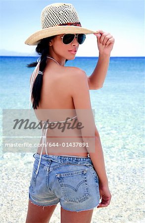 Young woman in hat and jean shorts on beach