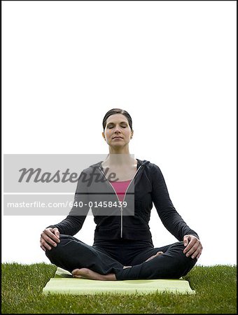 Woman doing yoga on mat on grass