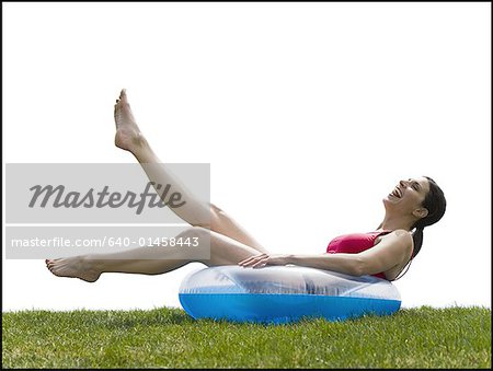 Woman in bikini lying in swimming ring on grass smiling