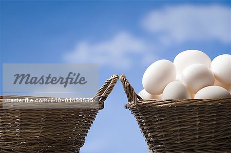 Einen leeren Korb und einen Korb voller Eier im Freien mit blauer Himmel