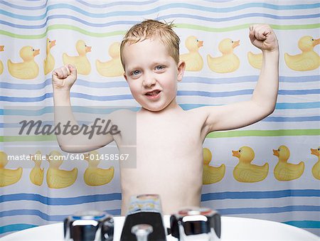 Boy flexing muscles in bathroom