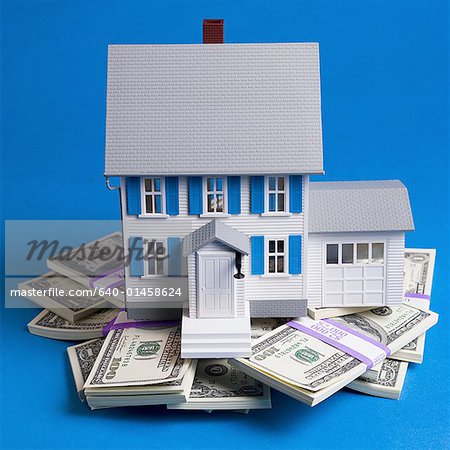 Toy house on pile of one hundred dollar bills