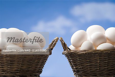 Two baskets filled with eggs outdoors with blue sky