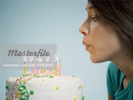 Voir le profil:: femme souffler les bougies sur le gâteau d'anniversaire